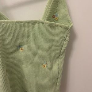 Green knit tank top with embroidered floral details.